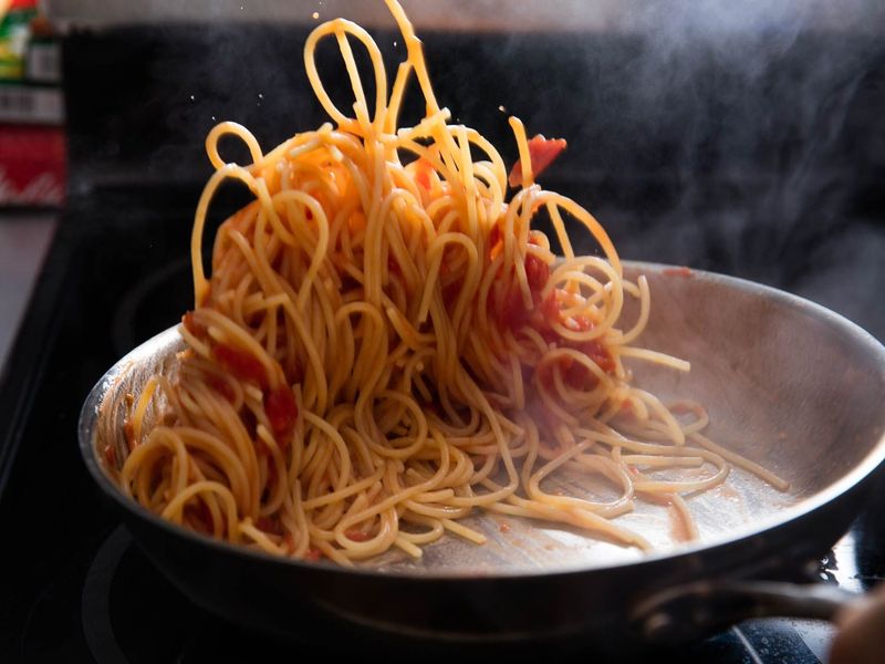 The wood-fired restaurant finishing pasta in a hot pan
