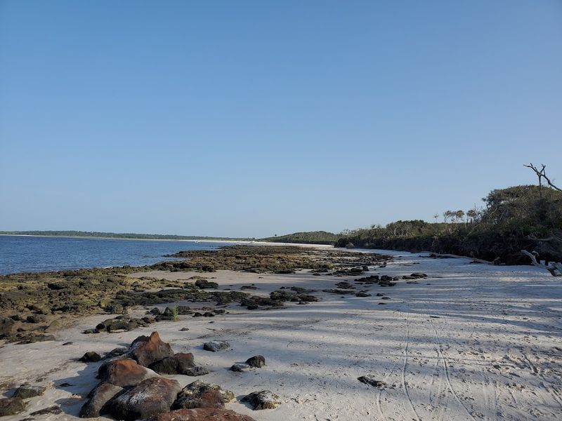 Soft White Sand That Contrasts The Dark Rocks